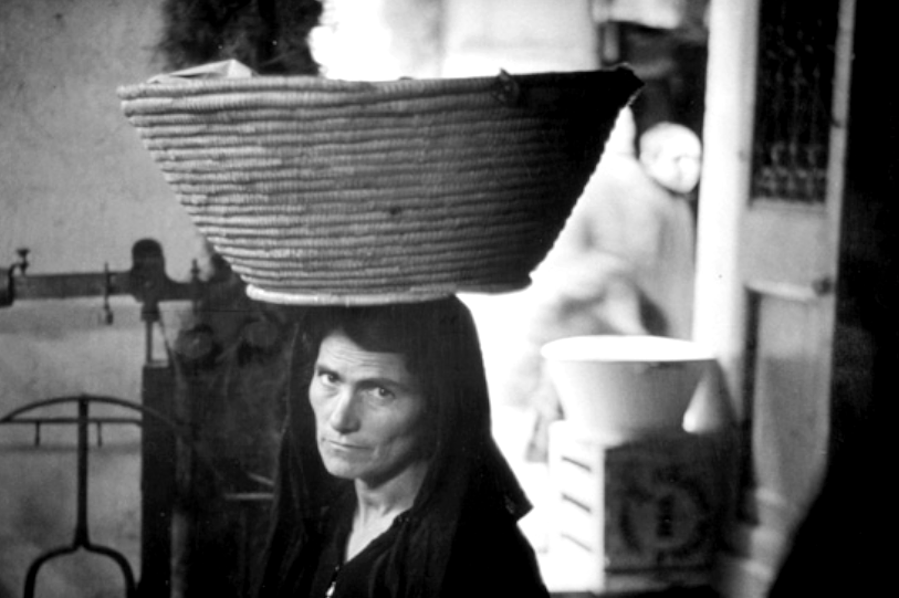 Retratu de fèmina chi giughet unu paniere subra de su capu. Fotografia de Werner Bischof, 1950